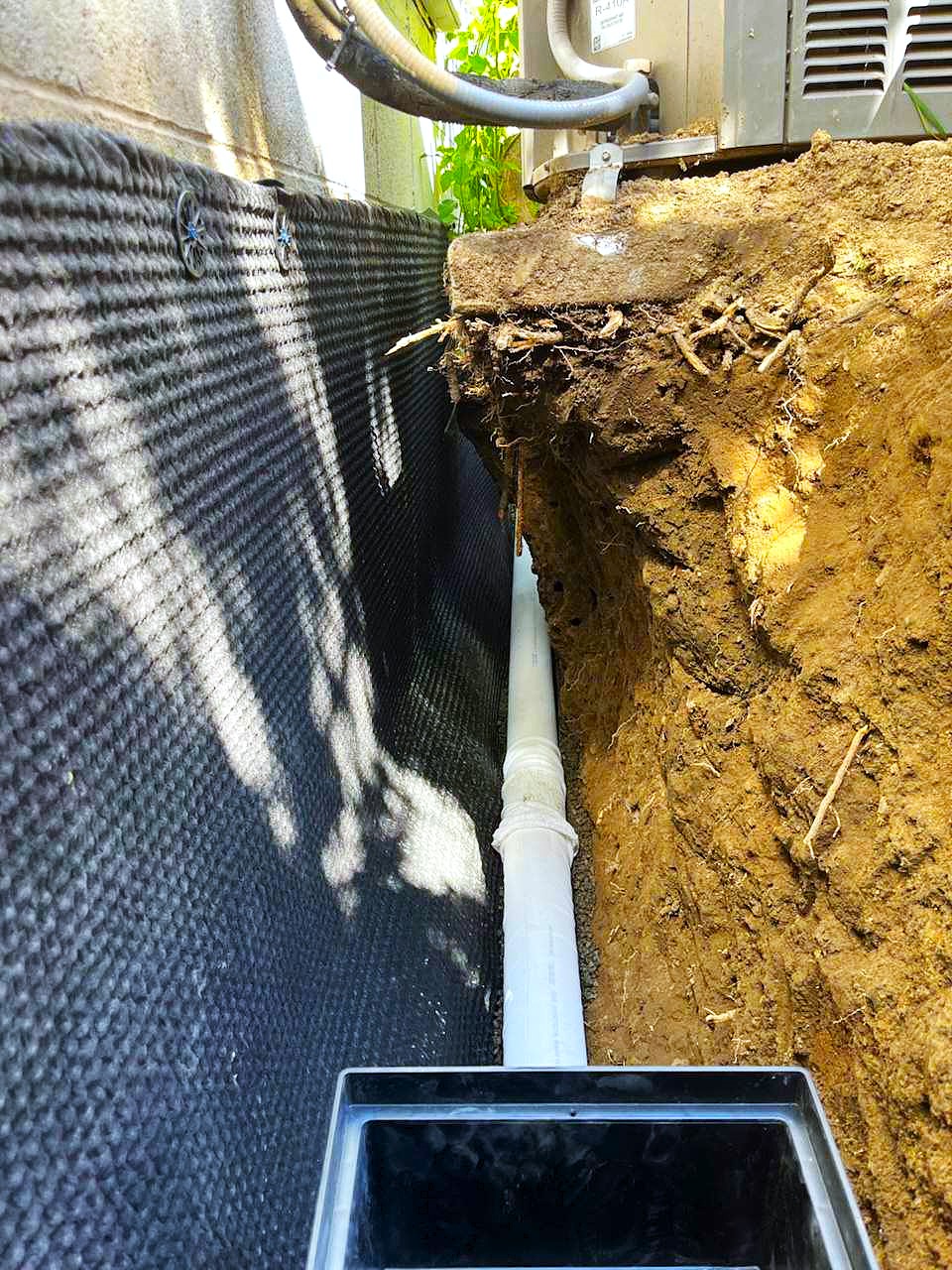 Filter Fabric around 4 inch perforated drainage pipe in a trecnh for a French drain installation in Seattle, WA